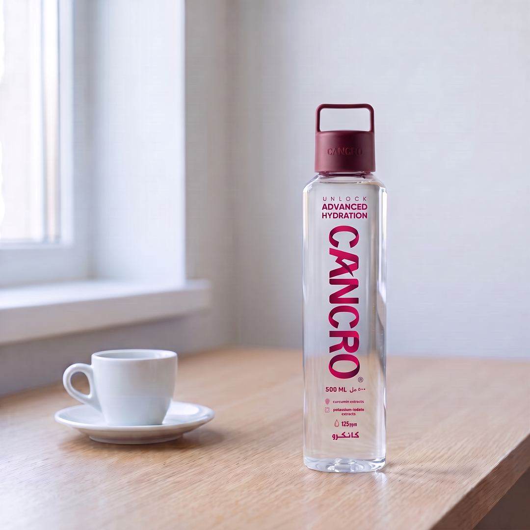A Cancro bottle beside a small coffee cup on a desk by a bright window